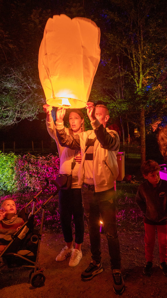 deux personnes tiennent une lanterne éclairé, de nuit, prête à s'envoler
