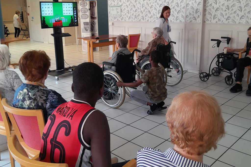 deux personnes âgées dans un fauteuil roulant devant un jeu vidéo