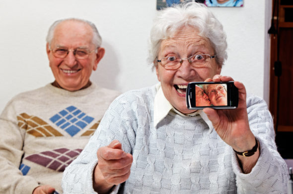 deux personnes âgées souriantes avec un téléphone