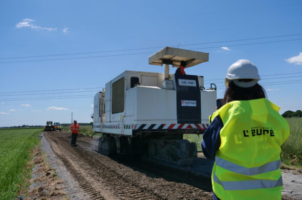 personnes avec un gilet jaune et une grosse machine devant elle