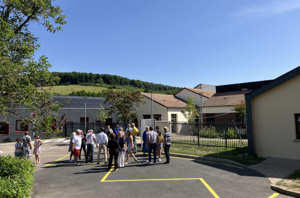 groupe de personnes devant un bâtiment et avec de la forêt en arrière plan