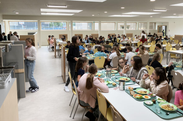 ensemble de personnes assis dans un cantine avec un plateau repas