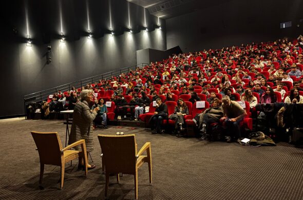 Salle de cinéma remplie de public avec une personne sur la scène