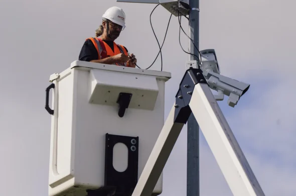 personne dans une nacelle en train d'installer une camera sur un poteau