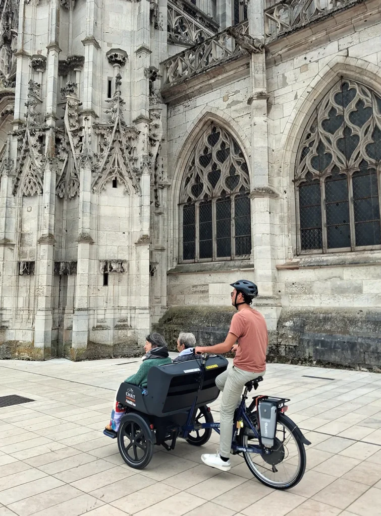 triporteur avec 3 personnes passant devant une église